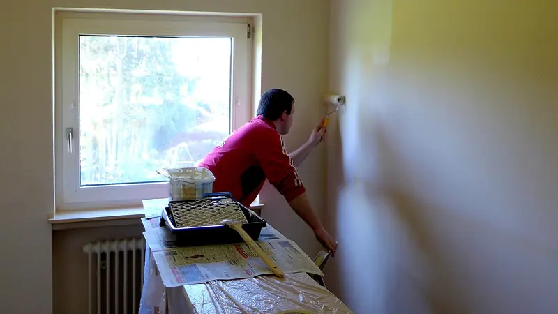 Malerarbeiten Aargau: Maler streicht in einem Wohnraum die Wand unter dem Fenster